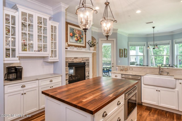 kitchen with pendant lighting, butcher block countertops, sink, appliances with stainless steel finishes, and a kitchen island