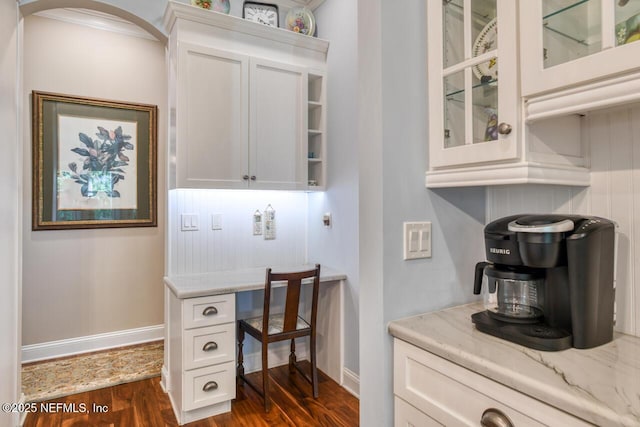 home office with dark hardwood / wood-style flooring and built in desk