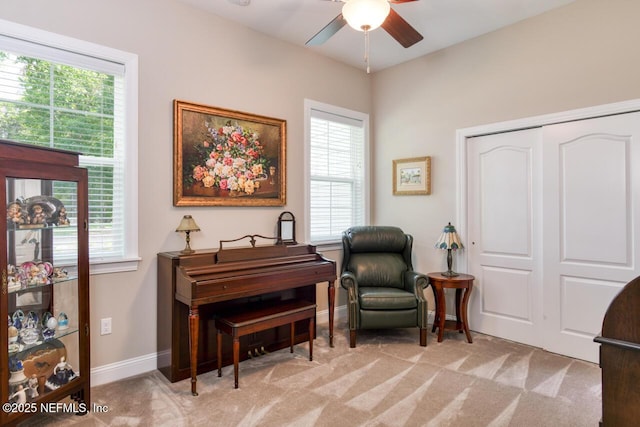 living area featuring light carpet and ceiling fan