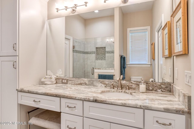 bathroom featuring vanity, toilet, and a shower with door