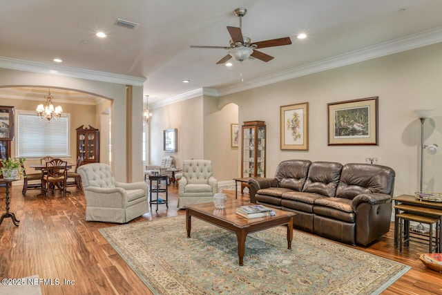 living room with ceiling fan with notable chandelier, ornamental molding, and hardwood / wood-style floors