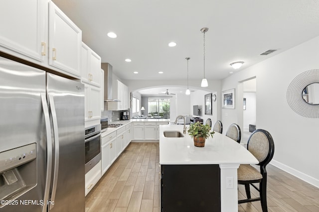 63 Park Lake Dr, Ponte Vedra, FL 32081 - kitchen with stainless steel appliances, a sink, wall chimney range hood, a breakfast bar, and light countertops