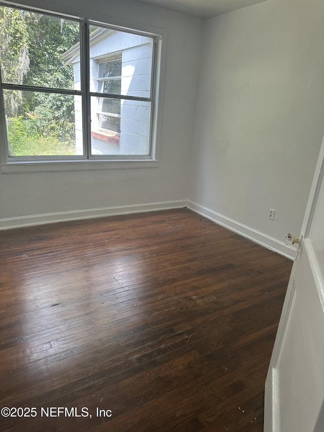 unfurnished room featuring dark wood-style flooring and baseboards