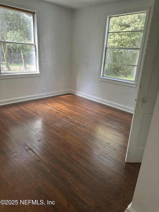 empty room featuring dark wood-type flooring and baseboards