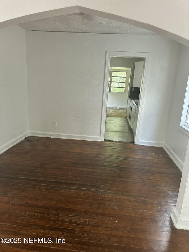 empty room with baseboards and dark wood finished floors