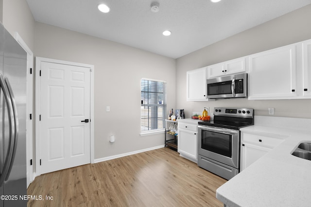 kitchen featuring white cabinetry, stainless steel appliances, sink, and light hardwood / wood-style flooring