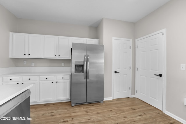 kitchen with appliances with stainless steel finishes, light hardwood / wood-style floors, and white cabinets