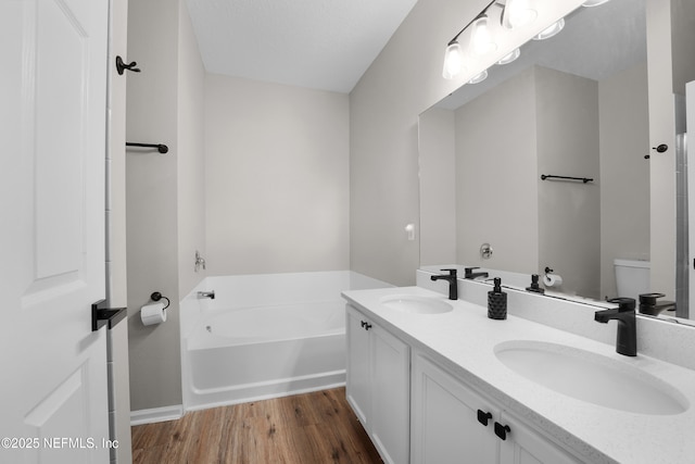 bathroom featuring wood-type flooring, toilet, a bathing tub, and vanity