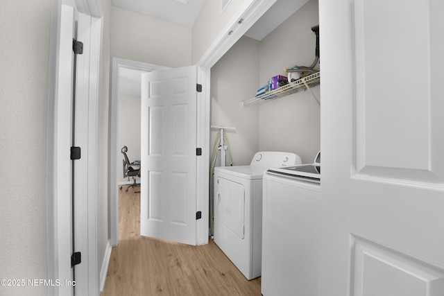 laundry area featuring washing machine and dryer and light hardwood / wood-style floors