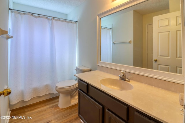 bathroom featuring hardwood / wood-style flooring, vanity, toilet, and a textured ceiling