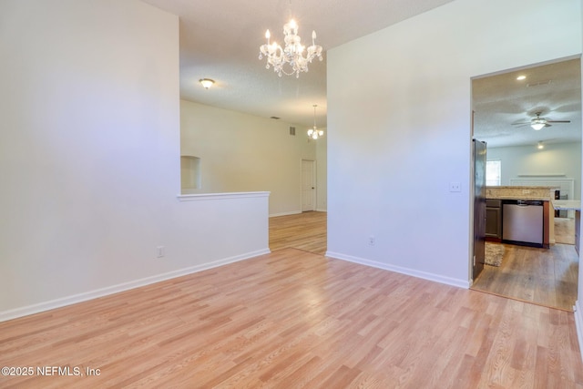 empty room featuring ceiling fan with notable chandelier and light hardwood / wood-style floors