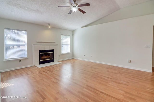 unfurnished living room with a fireplace, lofted ceiling, light wood-type flooring, ceiling fan, and a textured ceiling