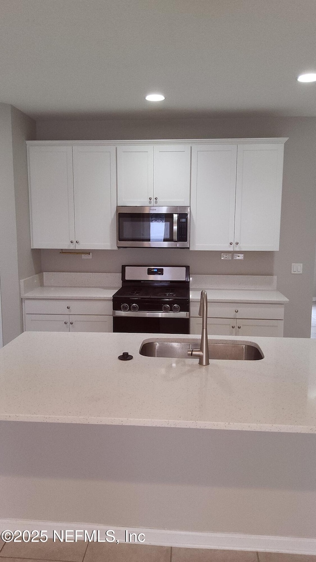 kitchen with white cabinetry, sink, light stone counters, and stainless steel appliances