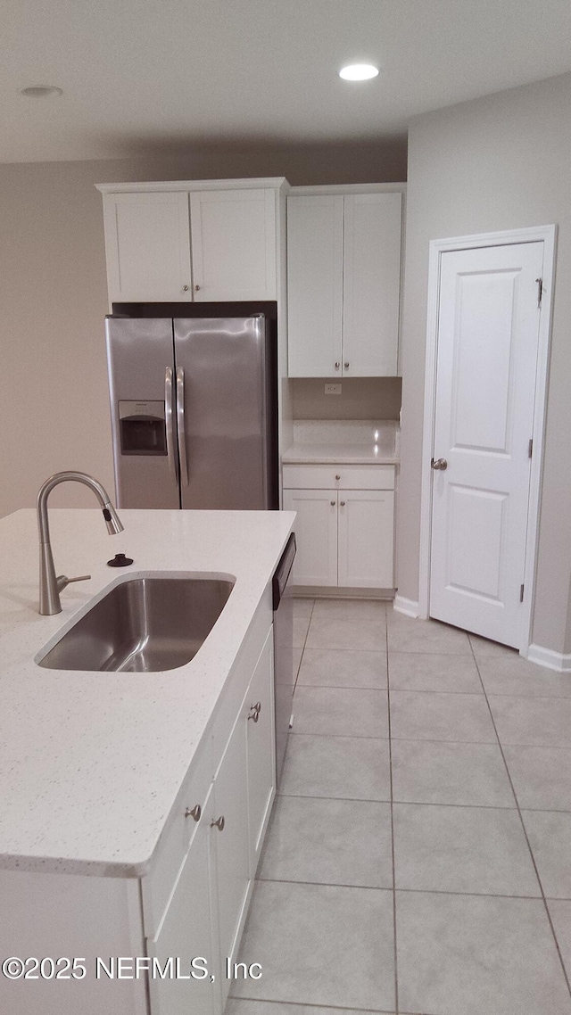 kitchen featuring sink, light tile patterned floors, appliances with stainless steel finishes, light stone countertops, and white cabinets