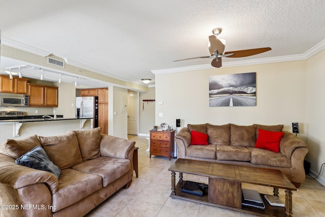 tiled living room featuring ceiling fan, rail lighting, a textured ceiling, and ornamental molding