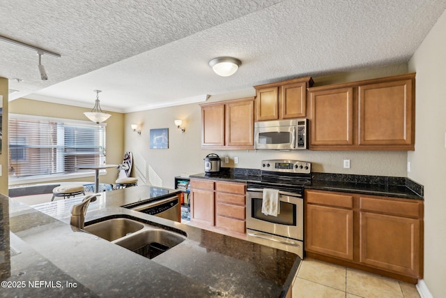 kitchen featuring sink, dark stone countertops, stainless steel appliances, and pendant lighting