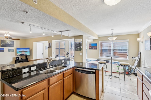 kitchen with hanging light fixtures, sink, stainless steel dishwasher, dark stone countertops, and crown molding