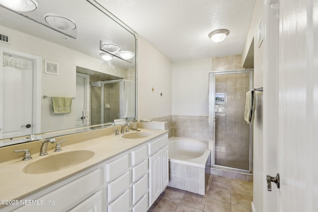 bathroom with tile patterned floors, independent shower and bath, vanity, and a textured ceiling