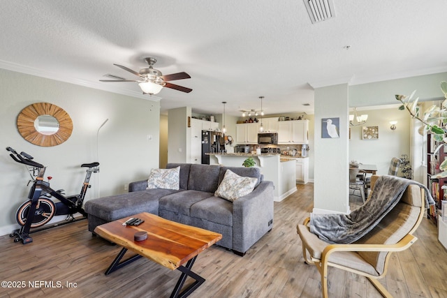 living room featuring crown molding, a textured ceiling, visible vents, and light wood-style floors