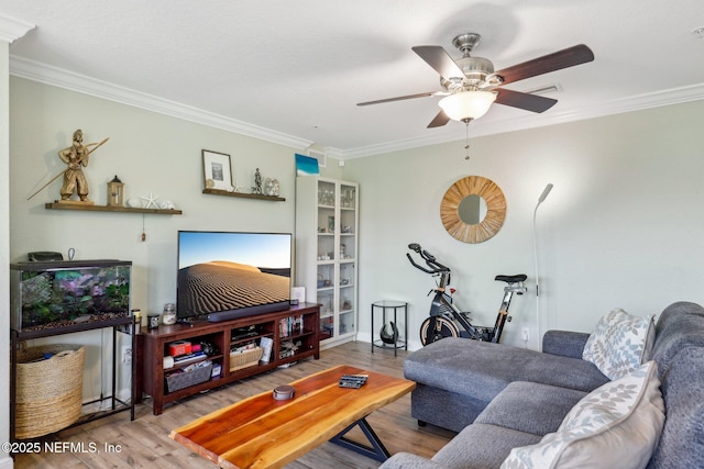 living area featuring a ceiling fan, visible vents, crown molding, and wood finished floors