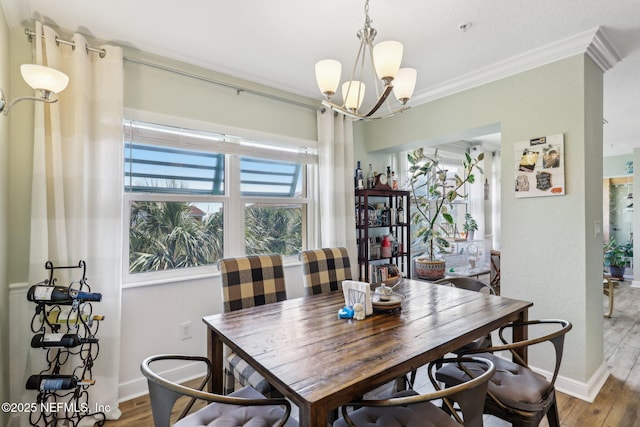 dining room featuring a chandelier, baseboards, wood finished floors, and crown molding