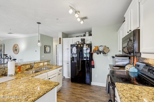 kitchen with hanging light fixtures, white cabinets, a sink, light stone countertops, and black appliances