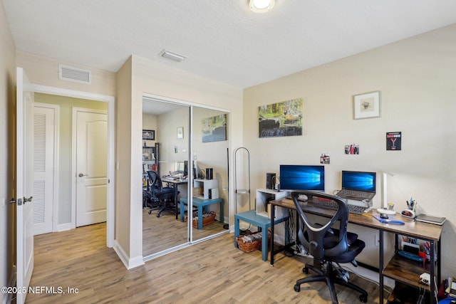 office area featuring light wood-style floors, visible vents, and baseboards