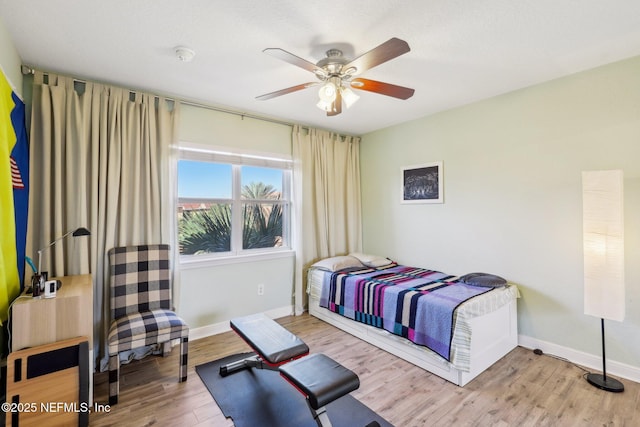 bedroom with light wood-style flooring, baseboards, and ceiling fan