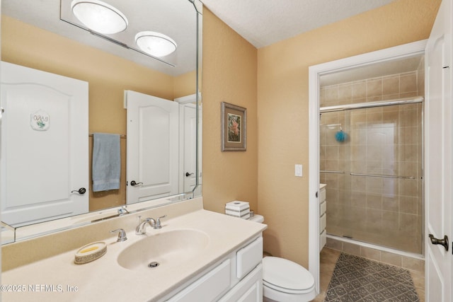 bathroom with toilet, a stall shower, and vanity