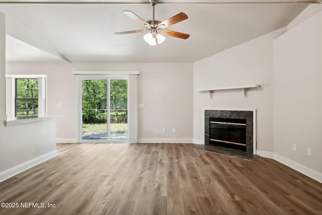 unfurnished living room with wood-type flooring, plenty of natural light, ceiling fan, and a fireplace