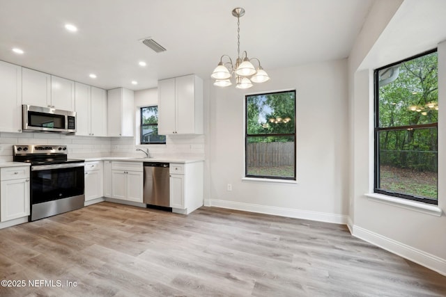 kitchen with white cabinetry, decorative light fixtures, tasteful backsplash, and appliances with stainless steel finishes