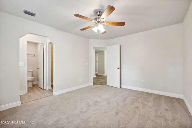 unfurnished bedroom featuring ceiling fan, light colored carpet, and connected bathroom