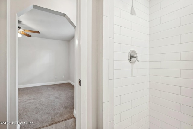 bathroom with ceiling fan and tiled shower