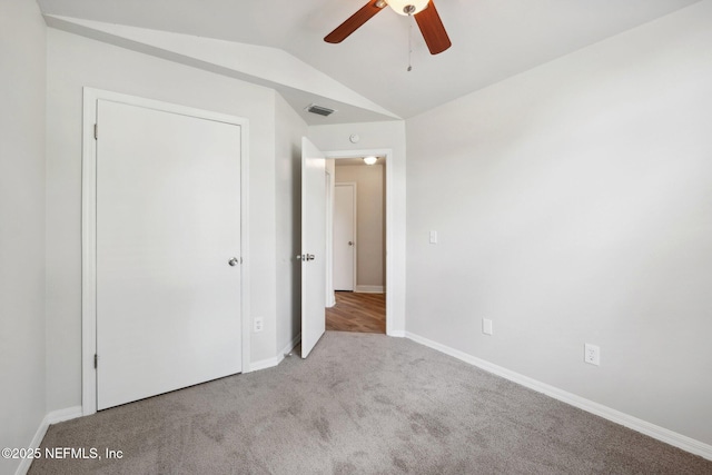 unfurnished bedroom with ceiling fan, vaulted ceiling, and light carpet