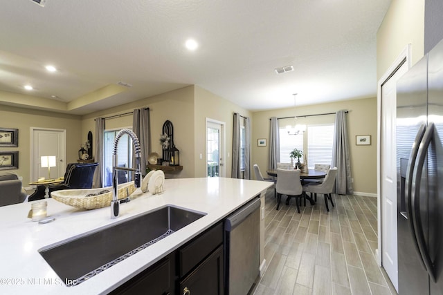 kitchen featuring light countertops, appliances with stainless steel finishes, dark cabinets, and pendant lighting