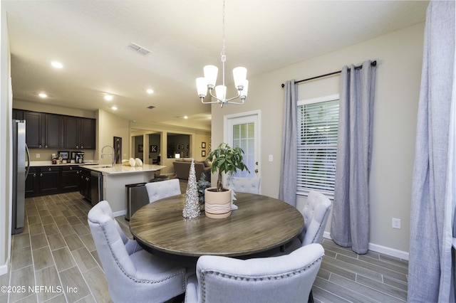 dining area featuring a chandelier, wood finish floors, visible vents, and baseboards