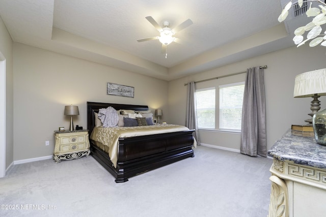 bedroom with light carpet, ceiling fan, baseboards, and a raised ceiling