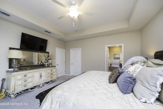 bedroom featuring light carpet, a textured ceiling, visible vents, and a ceiling fan