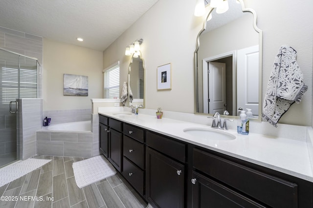 bathroom with a textured ceiling, double vanity, a sink, and a bath