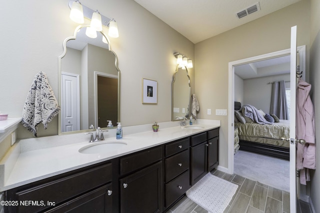 bathroom with ensuite bathroom, double vanity, a sink, and visible vents