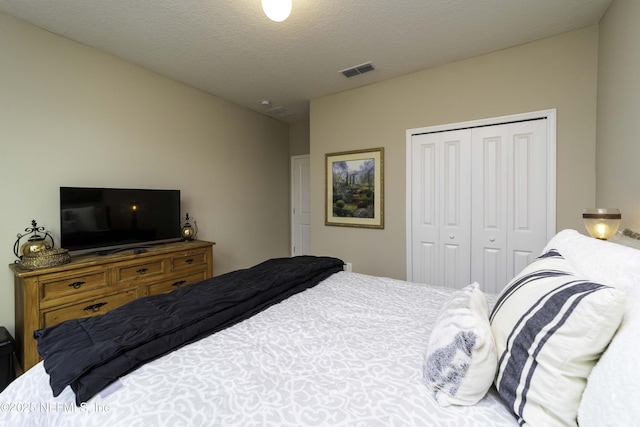 bedroom featuring a closet, visible vents, and a textured ceiling