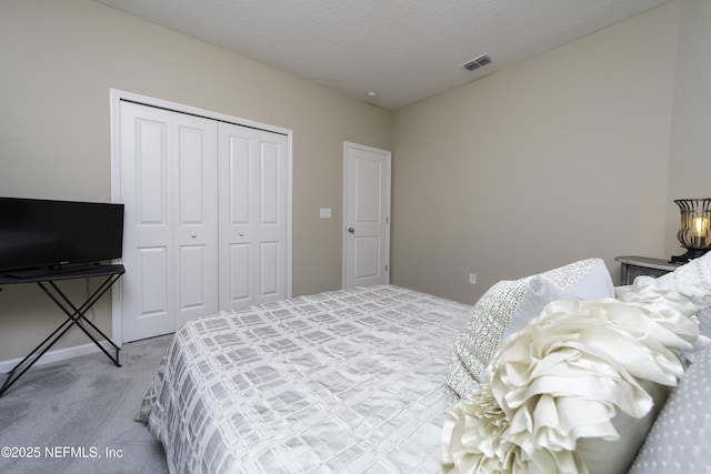 bedroom with a textured ceiling, carpet floors, a closet, and visible vents