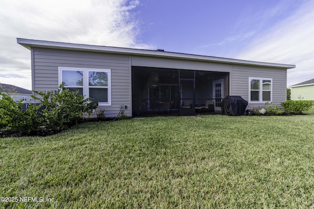 back of property with a lawn and a sunroom