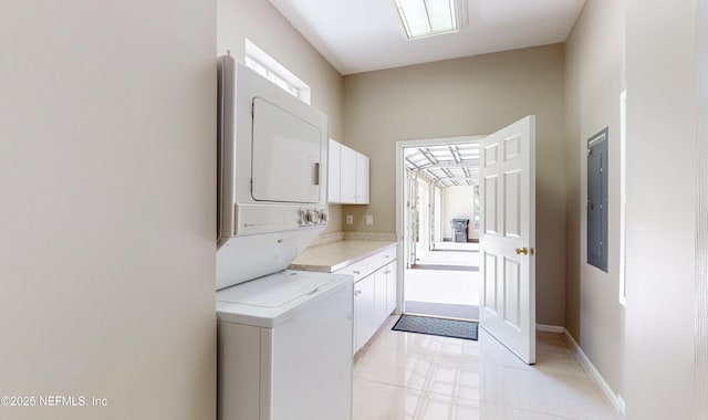 laundry area with stacked washer / drying machine, electric panel, and cabinets