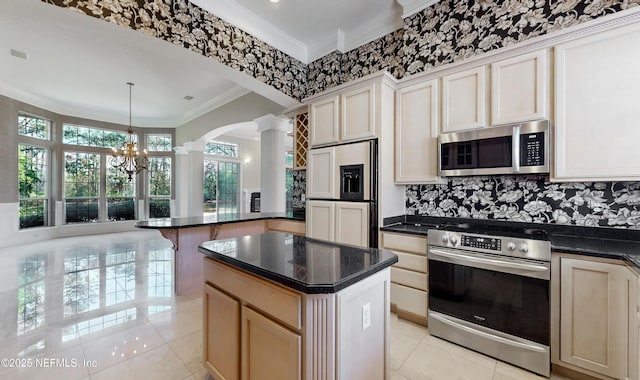 kitchen with a center island, hanging light fixtures, ornamental molding, appliances with stainless steel finishes, and decorative columns