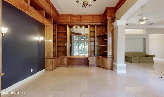 interior space with ceiling fan with notable chandelier, ornamental molding, built in shelves, and ornate columns