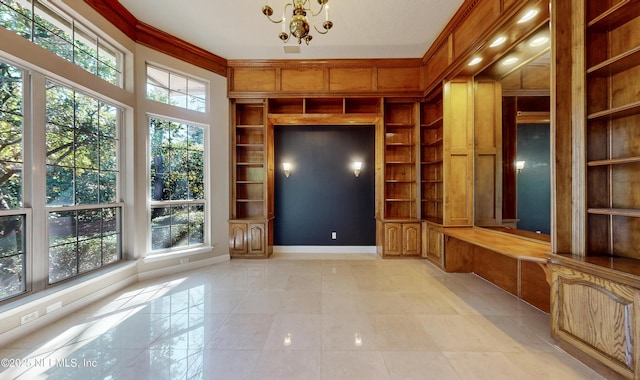 unfurnished living room with an inviting chandelier, built in shelves, and crown molding