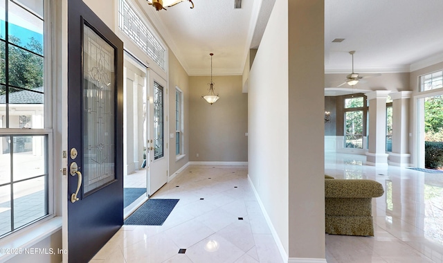 tiled foyer with ornamental molding and decorative columns