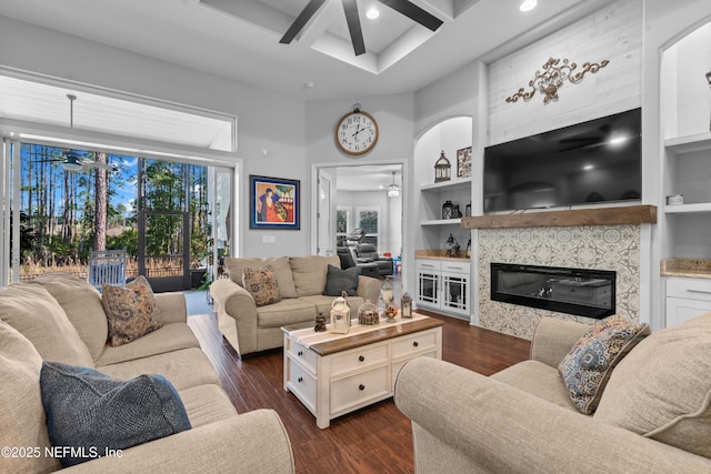 living room with built in shelves, coffered ceiling, dark hardwood / wood-style floors, ceiling fan, and a high end fireplace