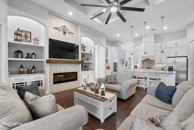 living room with coffered ceiling, ceiling fan, a high end fireplace, and dark hardwood / wood-style flooring